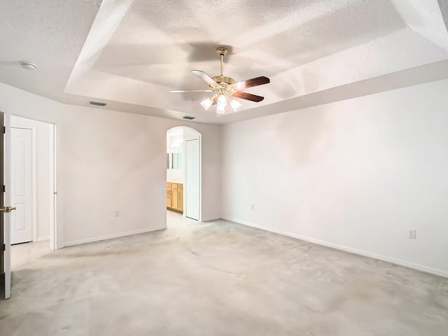 unfurnished room with ceiling fan, a textured ceiling, and a tray ceiling