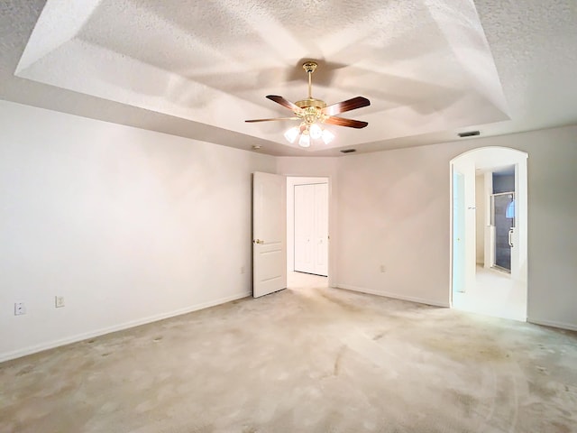 carpeted spare room with ceiling fan, a raised ceiling, and a textured ceiling