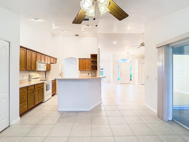 kitchen with light tile patterned floors, white appliances, ceiling fan, high vaulted ceiling, and a center island with sink