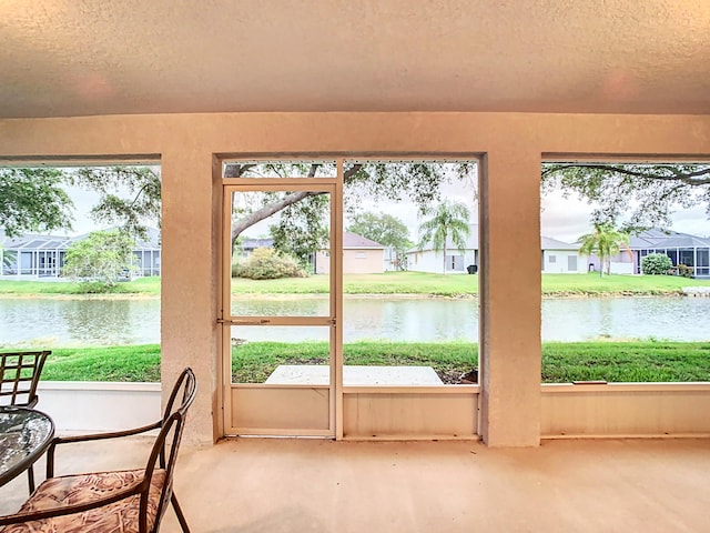 entryway featuring a textured ceiling, a healthy amount of sunlight, and a water view