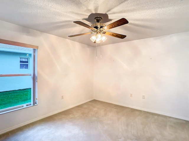 carpeted spare room with ceiling fan and a textured ceiling