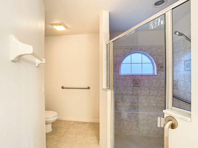 bathroom with a shower with shower door, tile patterned floors, and toilet