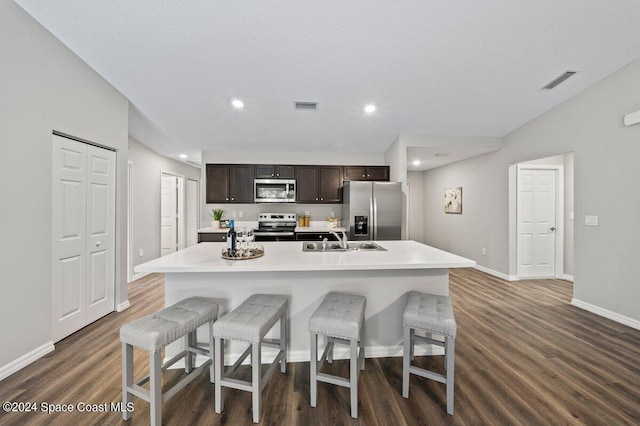 kitchen featuring dark wood-type flooring, stainless steel appliances, a center island with sink, and sink