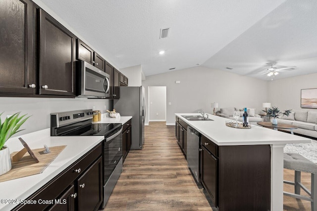 kitchen with lofted ceiling, a kitchen bar, dark wood-type flooring, sink, and stainless steel appliances