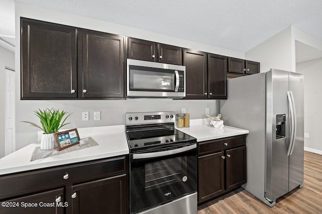 kitchen featuring appliances with stainless steel finishes, dark brown cabinetry, a textured ceiling, and light wood-type flooring