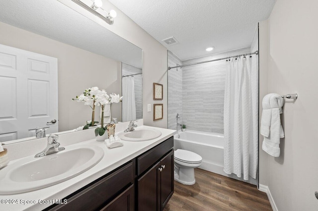 full bathroom featuring shower / bath combo, hardwood / wood-style flooring, toilet, vanity, and a textured ceiling