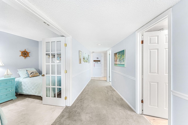 hall featuring light carpet and a textured ceiling