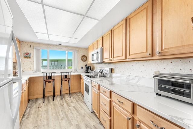 kitchen featuring a breakfast bar area, light hardwood / wood-style flooring, and white electric range