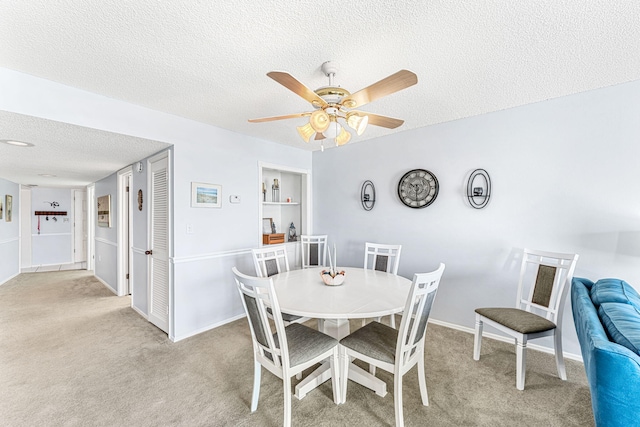 carpeted dining room with a textured ceiling and ceiling fan