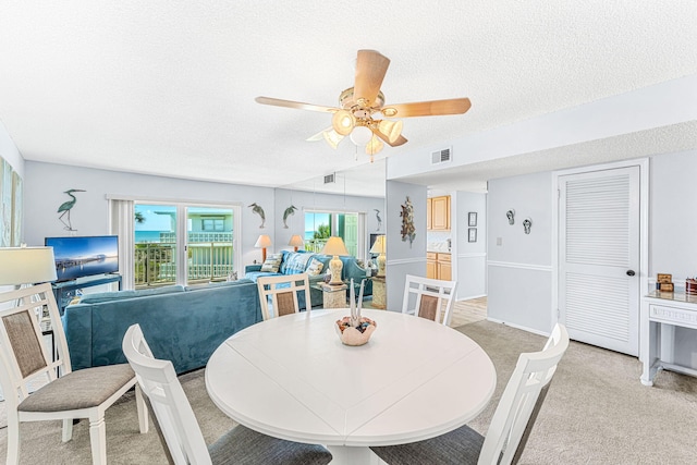 carpeted dining area with ceiling fan and a textured ceiling