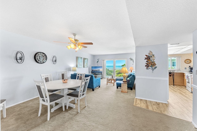 dining room with light carpet, ceiling fan, and a textured ceiling