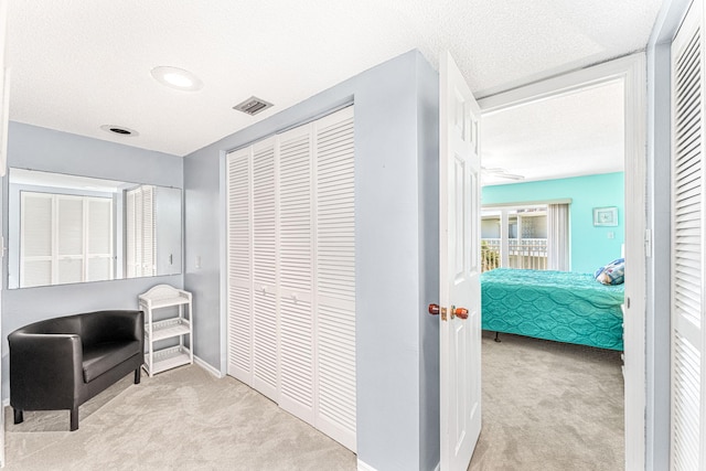 corridor featuring a textured ceiling and light colored carpet