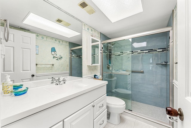 bathroom featuring tile flooring, an enclosed shower, toilet, vanity with extensive cabinet space, and a skylight