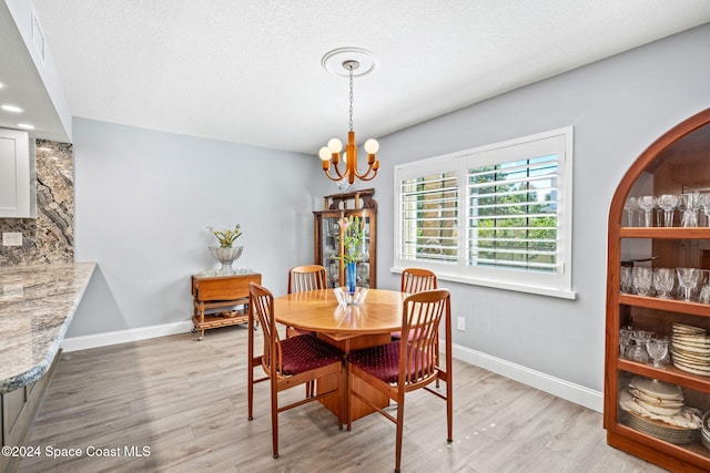 dining area with a textured ceiling, a chandelier, and light wood-type flooring