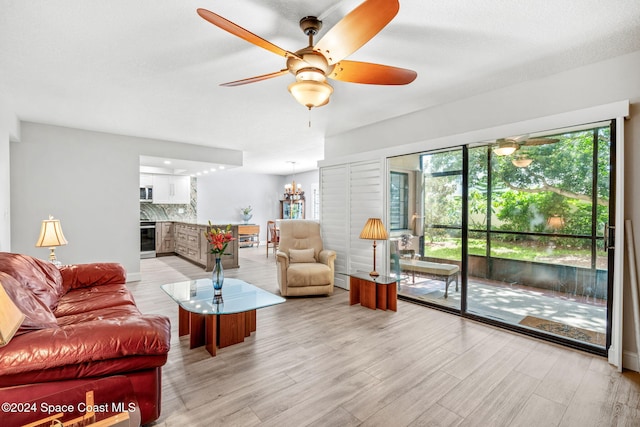 living room featuring light hardwood / wood-style flooring, a baseboard radiator, and ceiling fan with notable chandelier