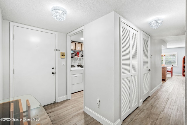 115 N Indian River Dr Unit 133, Cocoa, FL 32922 - entryway featuring light wood finished floors, a textured ceiling, baseboards, separate washer and dryer, and a chandelier
