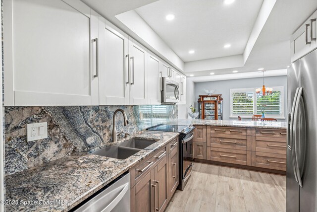 115 N Indian River Dr Unit 133, Cocoa, FL 32922 - kitchen featuring stainless steel appliances, a sink, light wood-type flooring, white cabinetry, and light stone counters