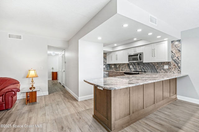 115 N Indian River Dr Unit 133, Cocoa, FL 32922 - kitchen featuring stainless steel appliances, light stone countertops, a peninsula, baseboards, and tasteful backsplash