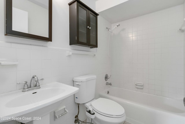 full bathroom with tiled shower / bath, toilet, sink, tile walls, and decorative backsplash