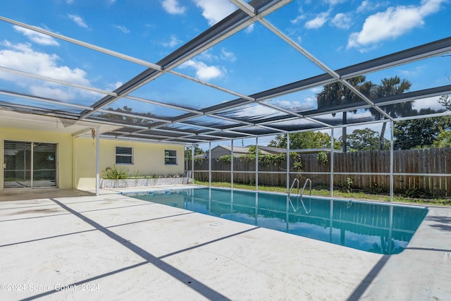 view of swimming pool with glass enclosure and a patio