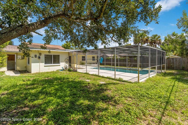 view of pool featuring a lawn, a patio, and glass enclosure