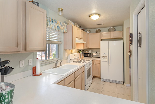 kitchen with a textured ceiling, white appliances, sink, light tile flooring, and light brown cabinetry