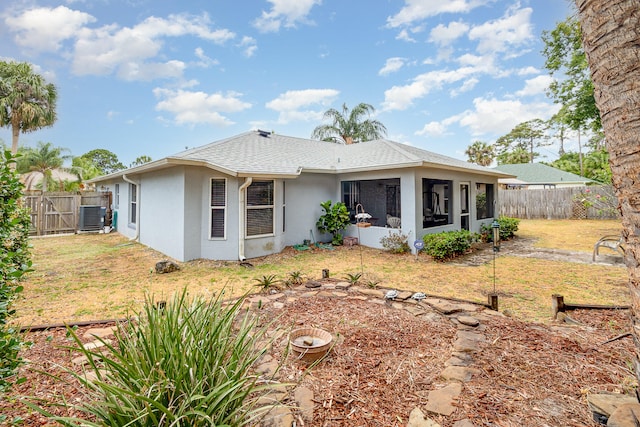 rear view of house with central AC unit and a yard