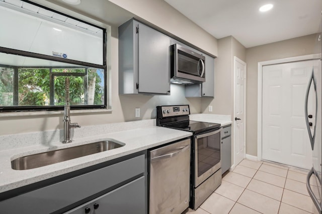 kitchen with stainless steel appliances, gray cabinets, sink, and light tile floors