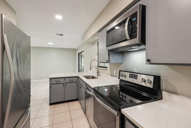 kitchen featuring kitchen peninsula, stainless steel appliances, gray cabinetry, sink, and light tile floors