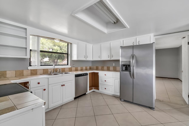 kitchen featuring white cabinetry, stainless steel appliances, light tile flooring, and sink