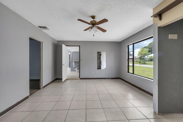 tiled empty room featuring ceiling fan and a textured ceiling