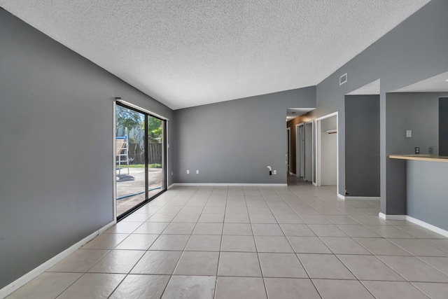 unfurnished room with a textured ceiling, light tile floors, and lofted ceiling