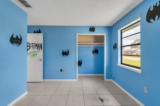 unfurnished room featuring a textured ceiling and light tile floors