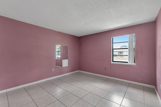 tiled empty room featuring a healthy amount of sunlight and a textured ceiling