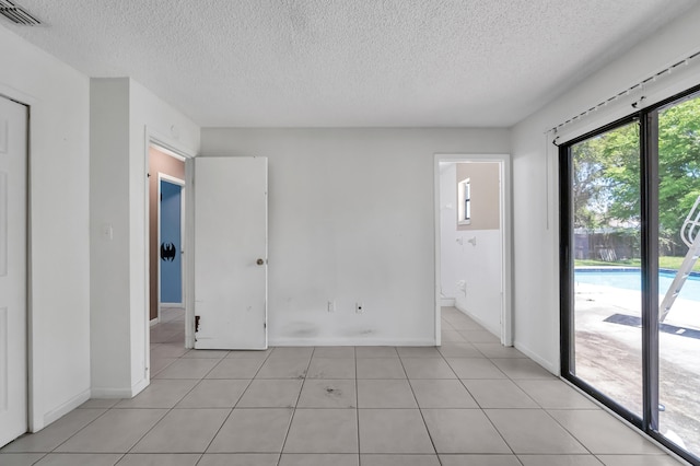 spare room featuring a textured ceiling and light tile floors