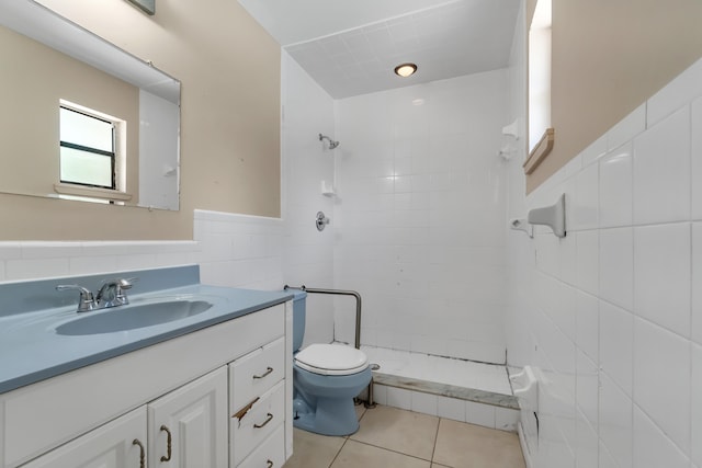 bathroom featuring tile floors, a tile shower, tile walls, vanity with extensive cabinet space, and toilet