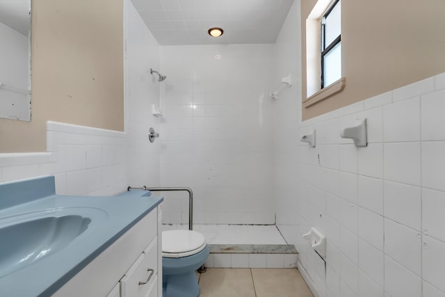 bathroom with tile floors, vanity, toilet, and tile walls