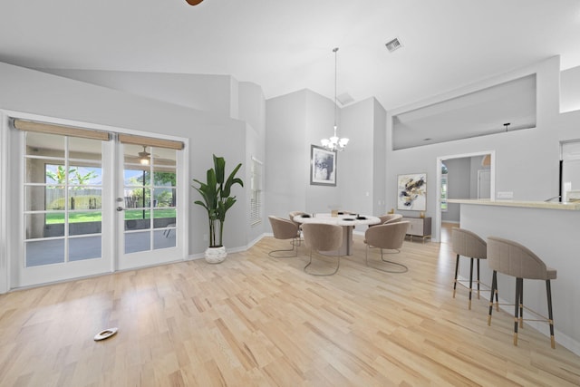 dining room featuring light hardwood / wood-style floors, high vaulted ceiling, and an inviting chandelier