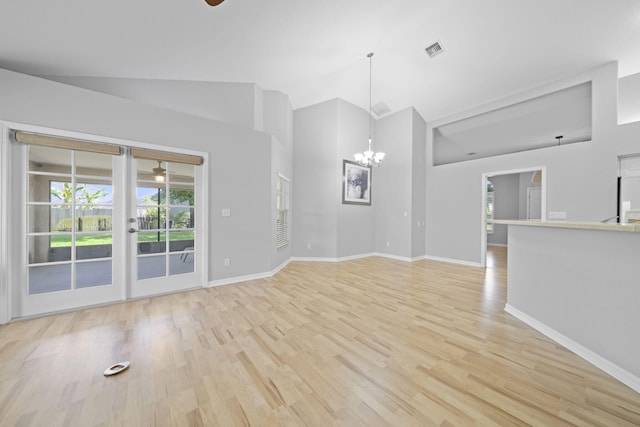 unfurnished living room featuring light hardwood / wood-style floors, high vaulted ceiling, and a notable chandelier