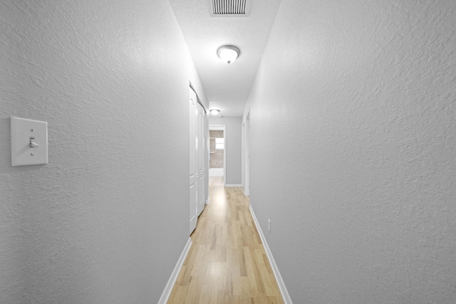 hall featuring light hardwood / wood-style floors and a textured ceiling