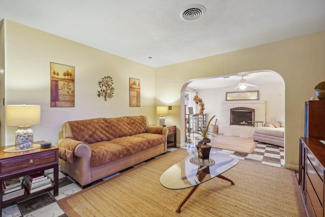 living room featuring tile floors, ceiling fan, and a fireplace