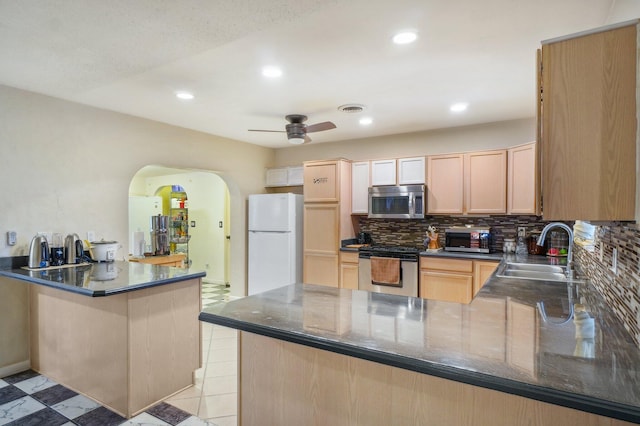 kitchen featuring white refrigerator, light tile flooring, kitchen peninsula, stove, and ceiling fan