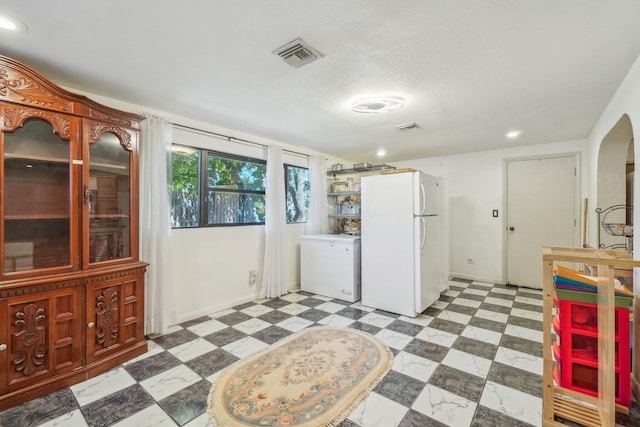 kitchen with white fridge, a textured ceiling, and tile floors