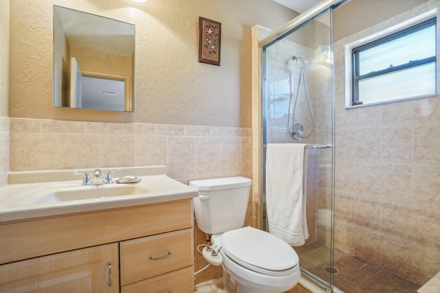 bathroom with tile walls, backsplash, toilet, a shower with door, and vanity