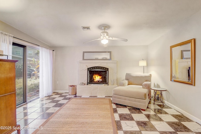 living area with visible vents, a premium fireplace, baseboards, and ceiling fan