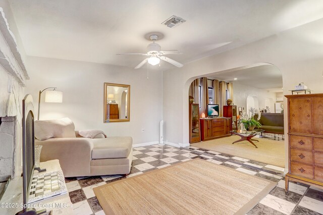 interior space with visible vents, arched walkways, baseboards, ceiling fan, and light floors