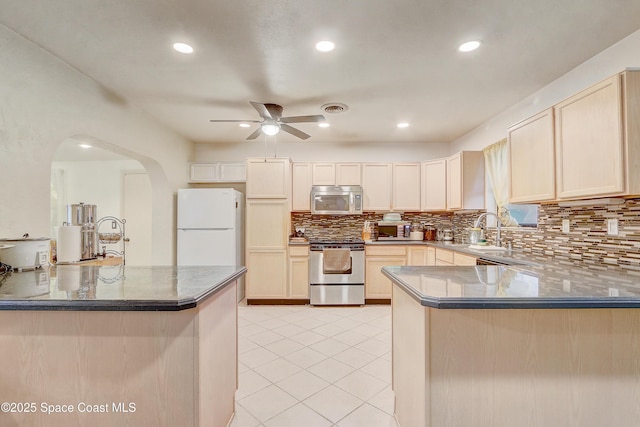 kitchen featuring light tile patterned floors, a peninsula, a sink, visible vents, and appliances with stainless steel finishes