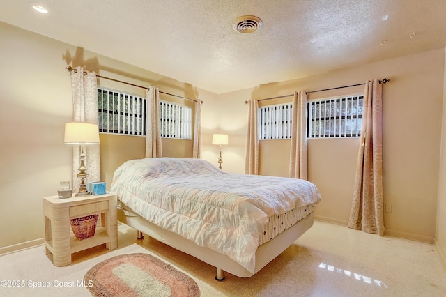 bedroom with visible vents, a textured ceiling, and baseboards