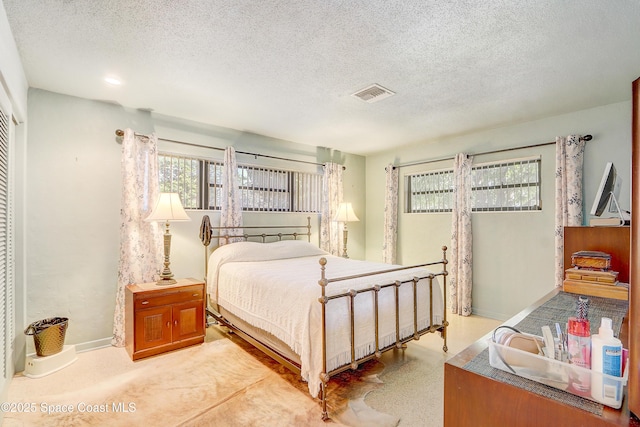 bedroom featuring a textured ceiling, visible vents, and baseboards