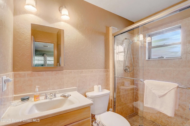 bathroom featuring toilet, a textured wall, a stall shower, and tile walls